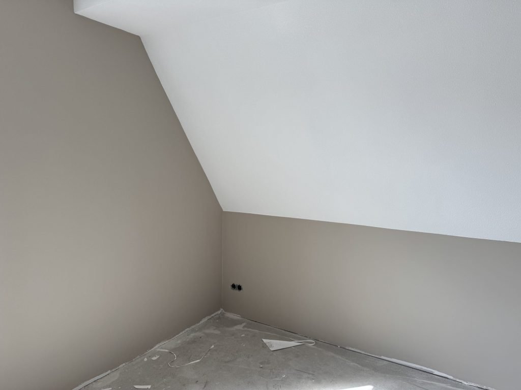 Zolderkamer in een nieuwbouwwoning met een schuine wand, klaar voor de afwerking